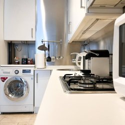 Encimera y electrodomésticos de la cocina del departamento Nicasio en La Latina, Madrid, con horno, cafetera, microondas y lavadora, gestionado por Stag Properties y destinado a alquiler vacacional