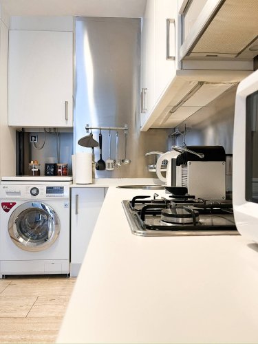 Encimera y electrodomésticos de la cocina del departamento Nicasio en La Latina, Madrid, con horno, cafetera, microondas y lavadora, gestionado por Stag Properties y destinado a alquiler vacacional